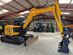 Side view of the yellow JCB 86C-2 with tractors in the background