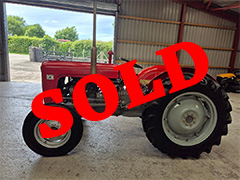Side view of the red Massey Ferguson 35 inside a barn with red SOLD writing